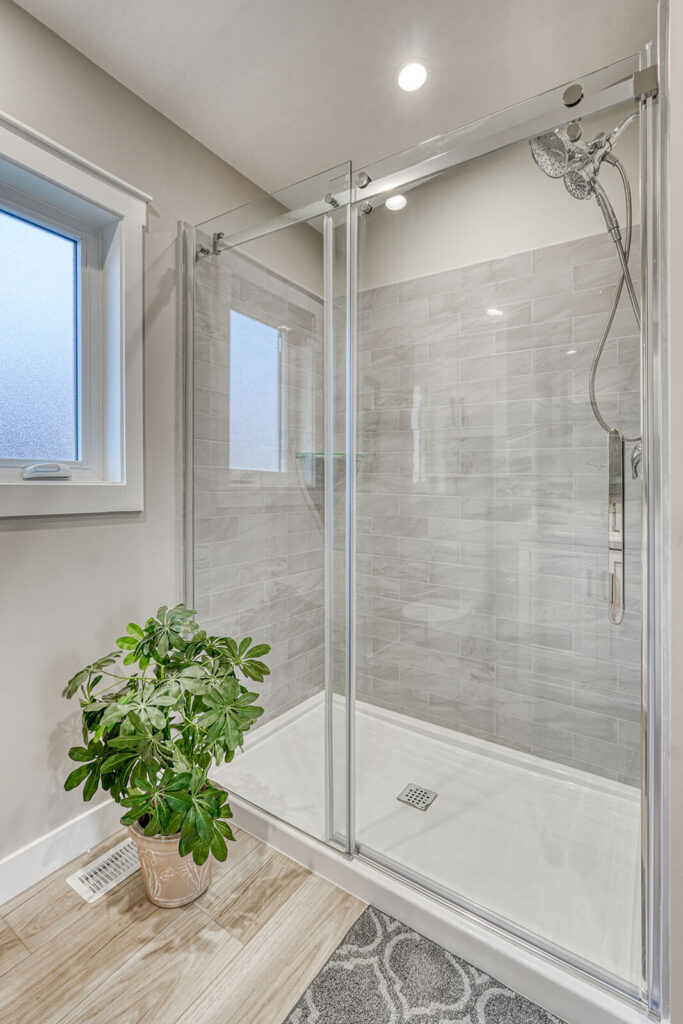 Glass enclosed shower with grey tile and modern fixtures