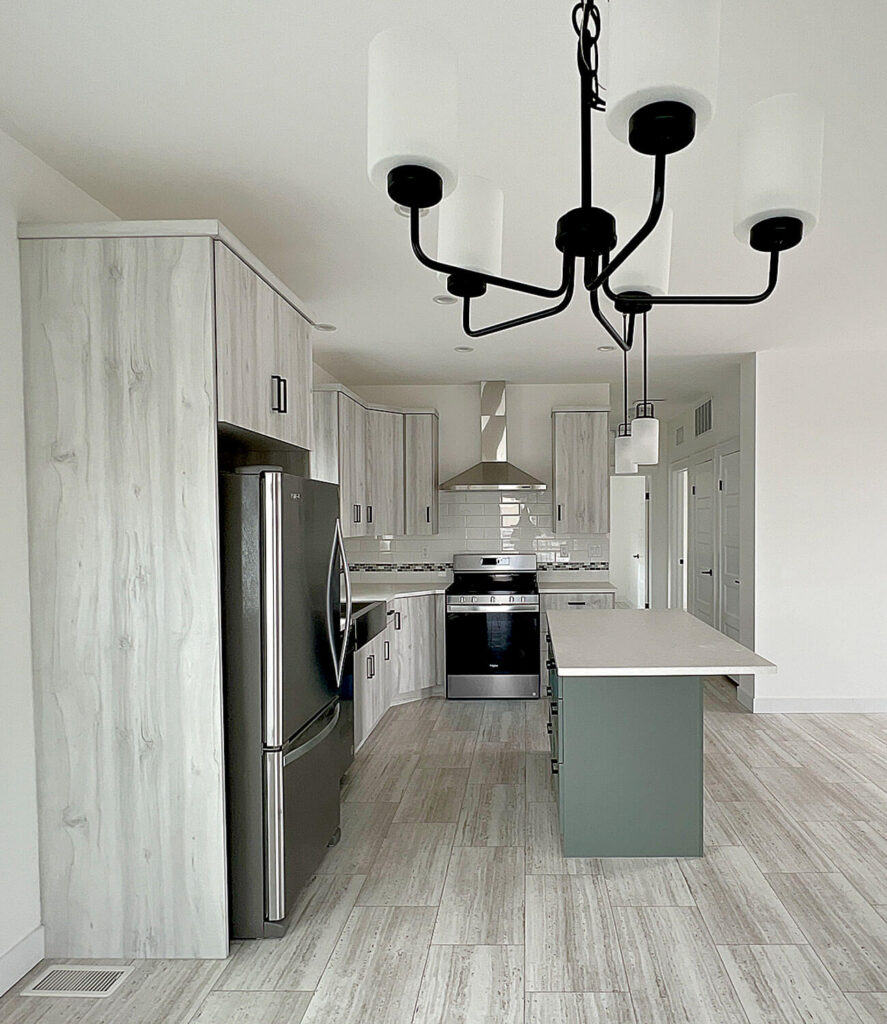 Light wood cabinets with green island and black chandelier