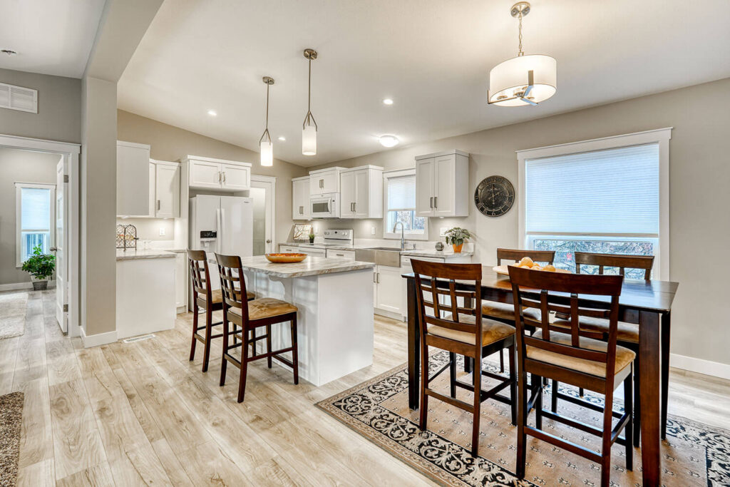 Open concept white kitchen with island bar seating and pendant lights