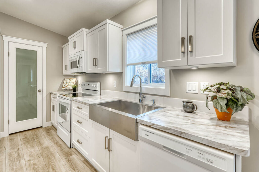 White cabinets with marble countertops and farmhouse sink